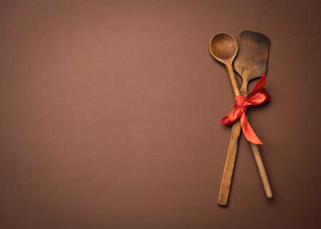 old spoon and spatula tied with red ribbon on a brown background, top view, copy spaceの写真素材