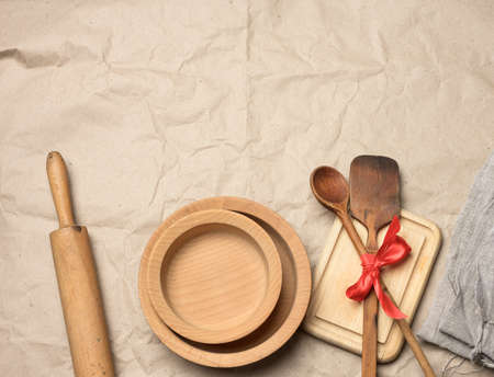 spoon and spatula tied with red ribbon on a brown paper background and wooden rolling pin, top view