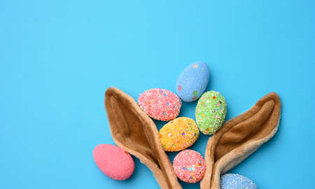 decorative easter eggs and long ears plush bunny toy on a blue background, copy spaceの写真素材