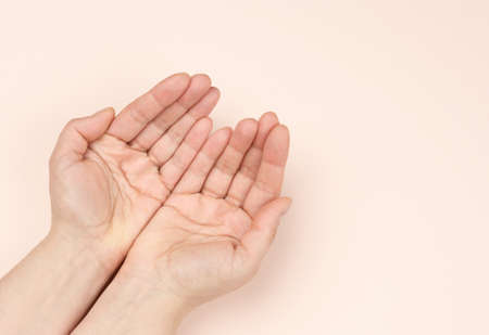 two female hands folded palm to palm on a beige background, top viewの写真素材