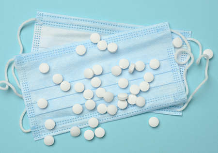 round white pills lie on a disposable medical mask, blue backgroundの写真素材