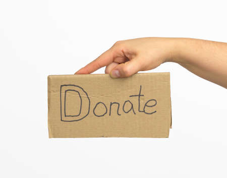 female hand holding a brown piece of cardboard with the inscription donate on a white backgroundの写真素材