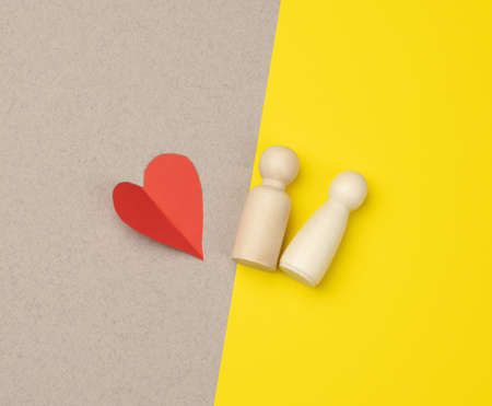 pair of wooden men of the bride and groom and red heart, yellow background, concept of love and...