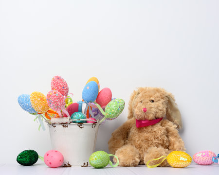 toy bunny sitting on a white background and decorative colorful easter eggs, festive backgroundの写真素材