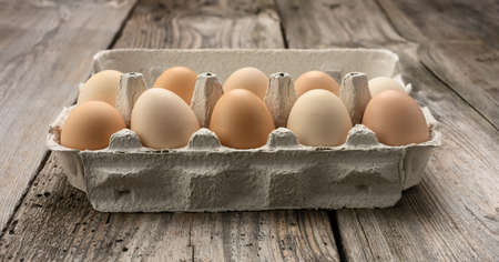 fresh whole brown eggs in paper packaging on a gray wooden background, close up