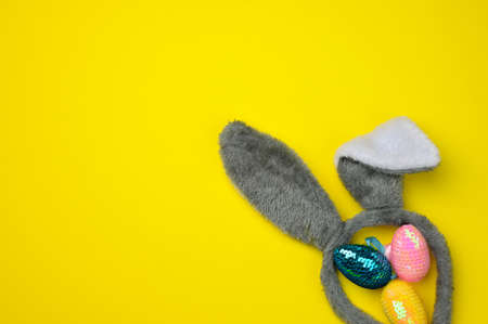 decorative easter eggs and long ears plush bunny toy on a yellow background, copy space