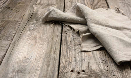 gray linen kitchen towel on a table made of old wooden boards, top view, copy space