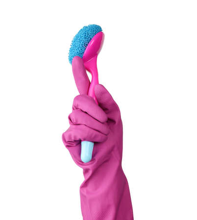 hand in a pink rubber glove for cleaning a house holds plastic brush with a handle on a white...