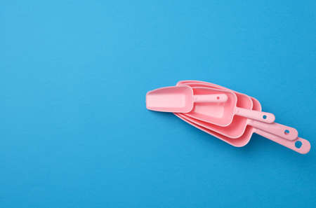 set of pink plastic kitchen scoops for bulk products on a blue background, flat layの写真素材