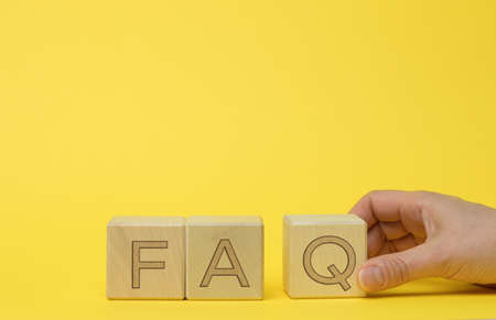 inscription FAQ (frequently asked questions) on wooden blocks on a yellow background. Q&A concept, help and tipsの写真素材