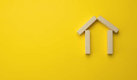 wooden miniature house on a yellow background. The concept of buying and selling a house, renting and leasing real estate, insurance, a place for an inscriptionの写真素材