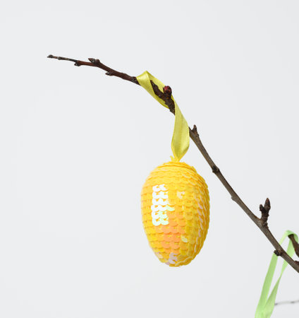 yellow decorative egg from sequins on a white background, easter backgroundの写真素材