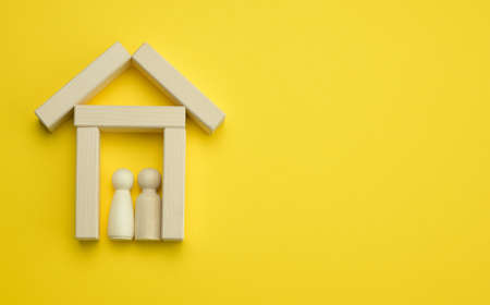 wooden miniature house on a yellow background. The concept of buying and selling a house, renting and leasing real estate, insurance, a place for an inscriptionの写真素材