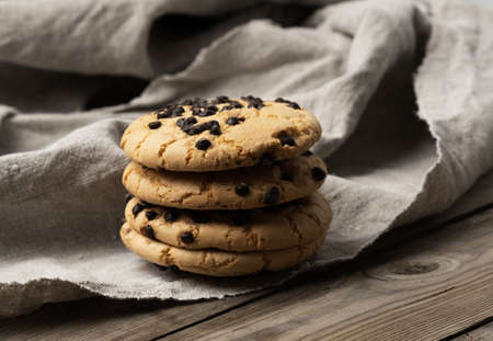 round cookies with pieces of chocolate on a textile towel, a stack of pastries