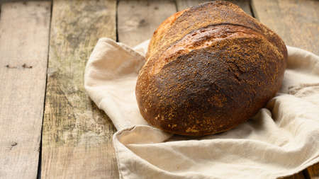baked round bread made from white wheat board on wooden table, close up