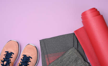 red sports mat pair of pink sneakers on a purple background. Things and gadgets for sports, flat layの写真素材