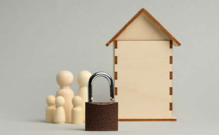 metal padlock on the background of a wooden miniature house and wooden figures of a family on a gray background. Data and private property security concept, security systemの写真素材
