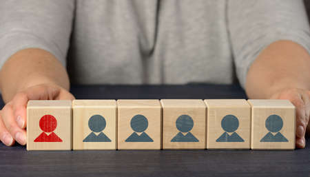 female hands hold wooden cubes with figurines. Employee search concept, staff recruitment. Selection...