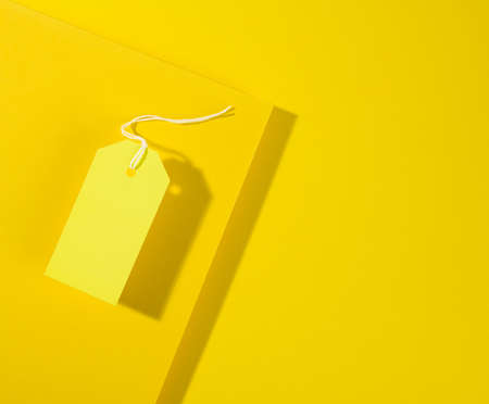 blank rectangular paper yellow price tag with white rope on yellow background, flat layの写真素材