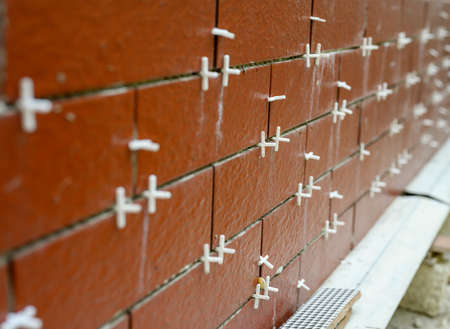 brown tiles in the process of laying. White auxiliary plastic crosses in the slots