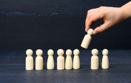 female hand holds a wooden figurine chosen from the crowd. The concept of finding talented...