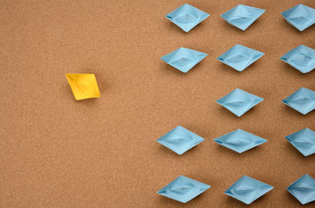 group of paper boats on a brown background. concept of a strong leader in a team, manipulation of the masses, following new perspectives, collaboration and unification. Startupの写真素材