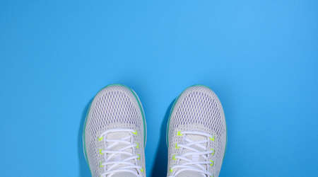 white women's sneakers with laces on a blue background, top view, bannerの写真素材