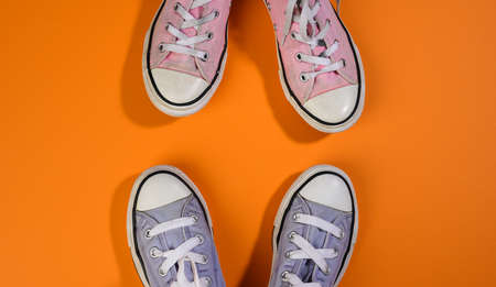 two pairs of textile sneakers on an orange background stand opposite each other. Dialogue and...