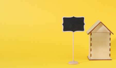 mini wooden house and chalk pointer on a yellow background. Real estate purchase concept, mortgage and home renovationの写真素材