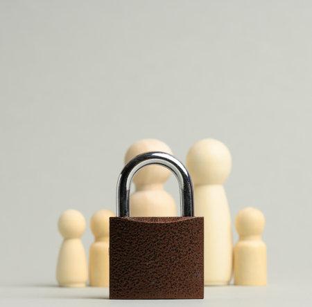 metal lock and a family of wooden figures on a gray background. Security concept, personal data, closed private information for the publicの写真素材