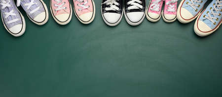 a lot of used textile sneakers on a green background, various sizes. Large family concept, friendship, copy spaceの写真素材