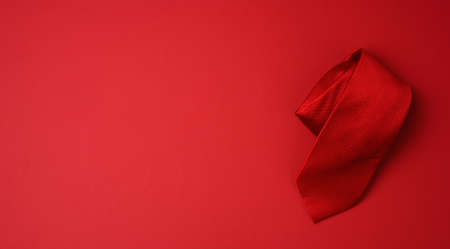 twisted silk red tie on a red background, copy space