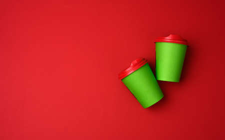 two green paper cups with a plastic lid on a red background, top view, copy space