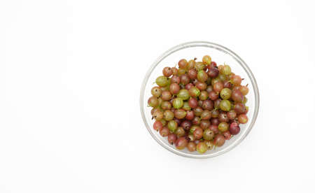 ripe green and red gooseberries in a transparent glass bowl on a white background, top viewの写真素材