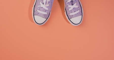 pair of textile sneakers on orange background, top view, bannerの写真素材