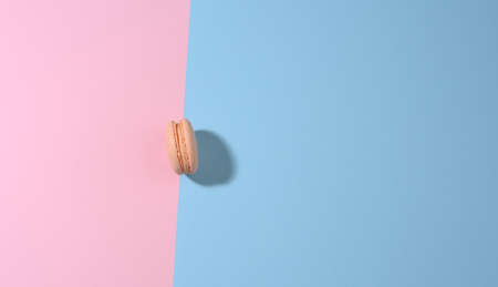 round pink macaron on a pink-blue background with shadow. Gourmet almond flour dessert, top viewの写真素材