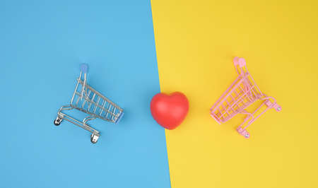 red heart in a miniature metal trolley from the store on a gray background. Organization donation,...