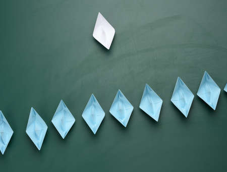 group of paper boats on a green background. concept of a strong leader in a team, manipulation of the masses, following new perspectives, collaboration and unification. Startupの写真素材