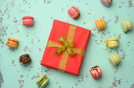 red square gift box with a bow and baked macarons on a green background, top viewの写真素材