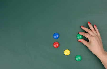 female hand attaches multi-colored magnets to a green board, place for an inscriptionの写真素材