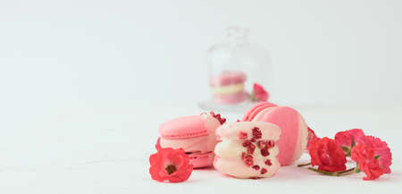 baked red strawberry macarons and rosebuds on a white table, gourmet almond flour dessert, close upの写真素材