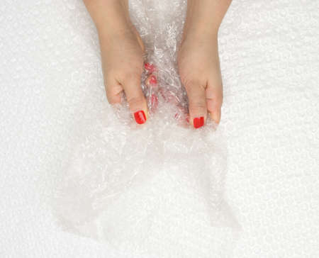 female hand holding crumpled piece of polyethylene with air bubbles on a white background, packing...