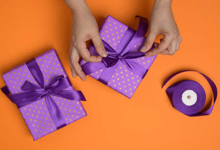 female hands tie a silk bow on a gift box, top viewの写真素材