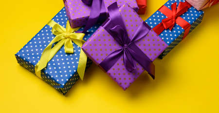 gift box tied with silk ribbon on a yellow background, top view. Festive backdropの写真素材