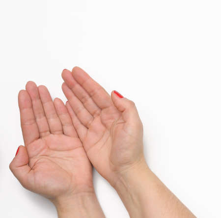 two female hands with red painted nails in a prayer pose on a white background, top view