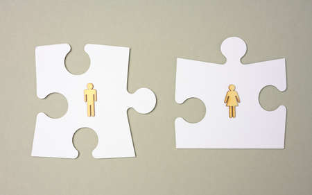 white puzzles and wooden men on a gray background. Recruitment concept, team compatibility,...