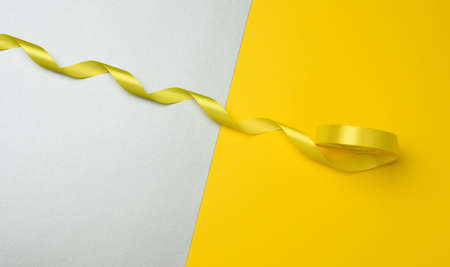 twisted yellow textile ribbon for decoration on a yellow-gray background, view from the topの写真素材