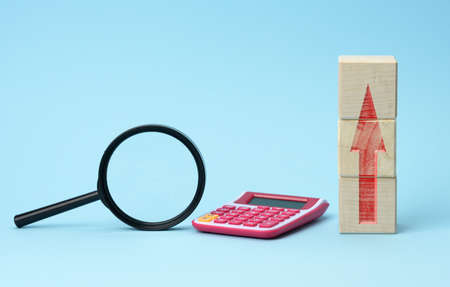 magnifier and calculator on a blue background. Income and expense growth concept, budget calculationの写真素材