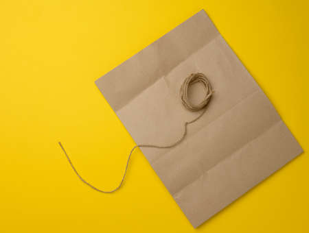 blank brown kraft paper bag and jute rope on yellow background, flat layの写真素材