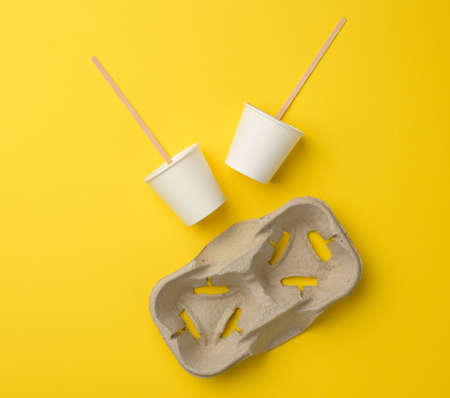 disposable white paper cups, wood sticks and paper tray on yellow background. Takeaway beverage containerの写真素材